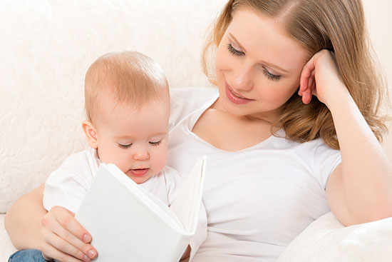 Kvinde læser bog med baby